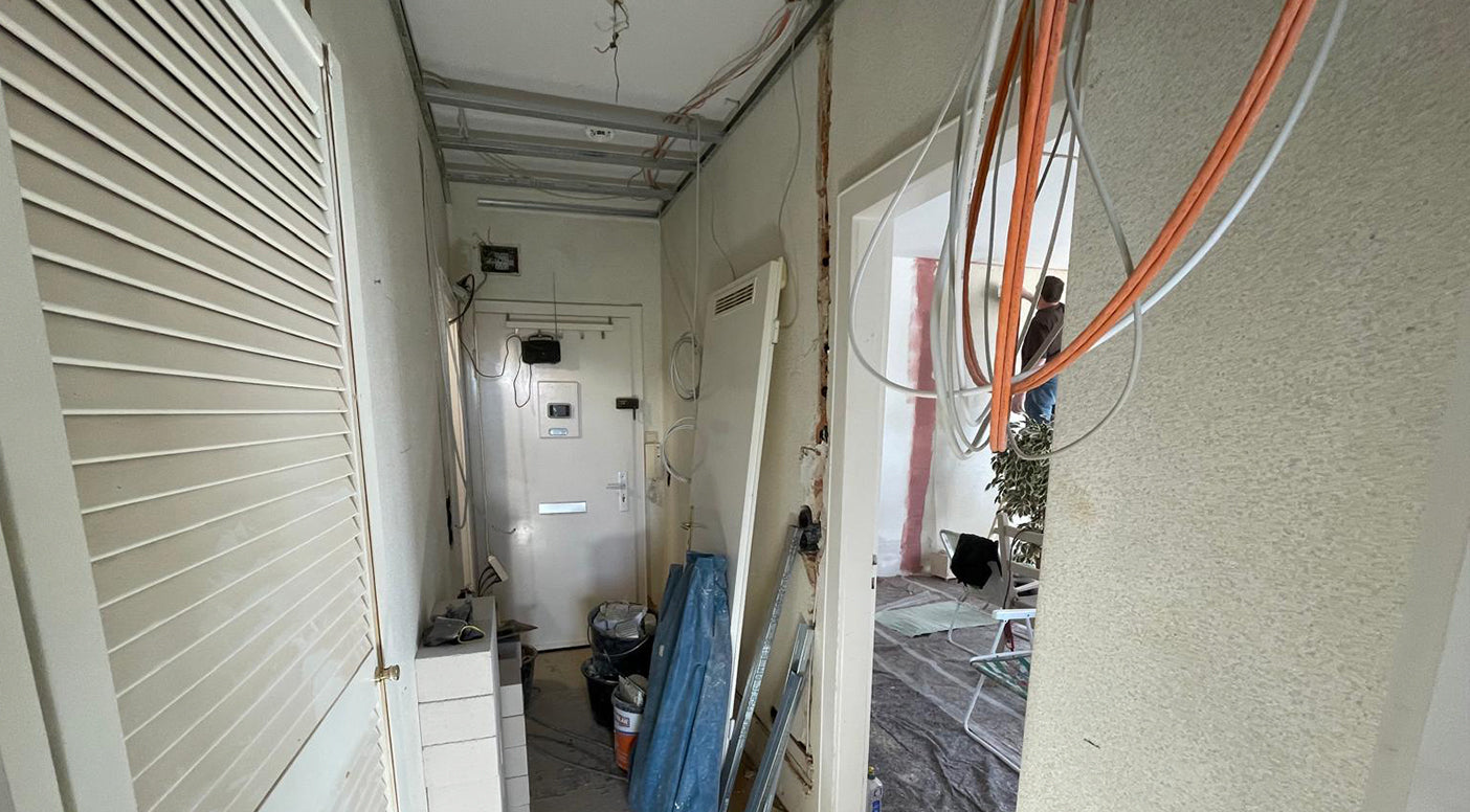 Schlüsselfertige Sanierung in Hannover. Hier sehen Sie einen Flur während der Sanierung. Mit heraushängenden Kabeln. und offenen Wänden.
